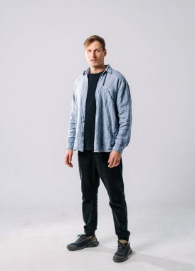 Stüdyo ortamında genç bir adamın sıradan portresi. Genç bir adam minimalist bir stüdyoda, günlük giysiler içinde yaratıcı bir proje için poz veriyor..