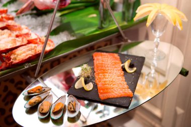 Somon ve kabuklu deniz ürünleri tabağı. Lezzetli bir deniz ürünleri tabağı taze somon, istiridye ve limon dilimlerini cam bir yüzeyde güzelce sergiliyor..