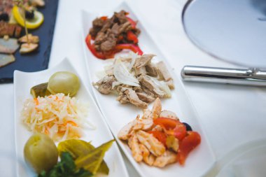 Et ve sebze tabağı masada. Canlı bir tabak et, taze sebze ve turşulu şeyler yemek masasında güzelce sergileniyor..