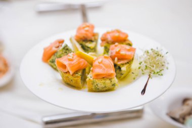Lezzetli somon ısırığı tabağı. Bir tabak sergisi, lezzetli bazlı bir yatakta nefis bir somon ısırığı, otlarla süslenmiş, gurme yemek için mükemmel..
