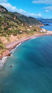 Kuzey Atlantik Okyanusu kıyısındaki köye yaklaşıyoruz. Sahilin muhteşem manzarası, kayalar suya doğru iniyor. Azorean Adaları. Dikey video.