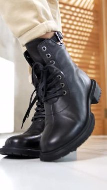 Bağcıklı ve yuvarlak burunlu şık siyah deri çizmeler. Açık renk kot giyen manken, stüdyoda şık ayakkabılar giyer. Kapat..