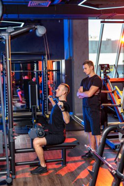 Modern jimnastik salonunda iniş egzersizi yapan bir adam. Bir adam gece boyunca hareketli ve iyi aydınlatılmış bir spor salonunu çalıştıran bir antrenör, iniş çıkışını tamamlar..