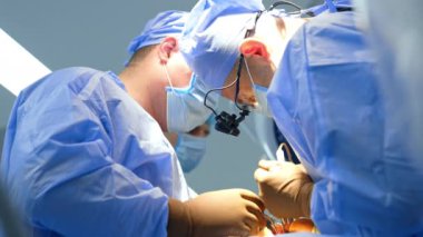 İşbirlikçi iki doktor, hastanın vücudundaki kesikteki aletleri kullanıyor. Nöroşirürji yapan profesyonellere düşük açılı bakış açısı.