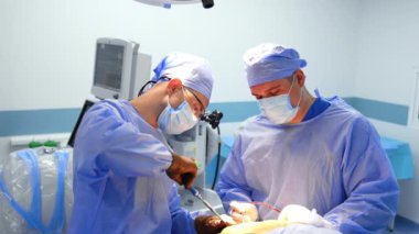 İki ortak çalışan doktor sinir cerrahisinde cerrahi aletler kullanıyor. Baş cerrah tornavida takıyor..
