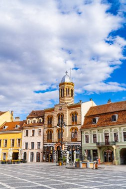 Braov 'un tarihi mimarisinde güneşli bir gün. Braov 'un güzel tarihi binalarının parlak gökyüzünün altında çarpıcı saat kulesini ve büyüleyici caddeleri gösteren manzarası..