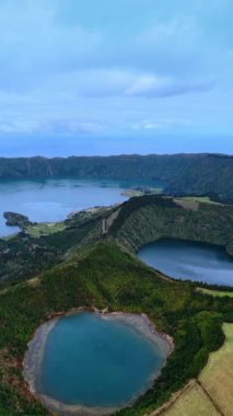 İçinde göller olan iki uyuyan volkan kraterinin üzerinde uçuyorlar. Azorean Adaları 'nın manzarası. Dikey video.