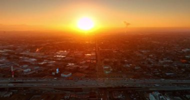 Araç Los Angeles, California, ABD otobanlarından geçiyor. Metropolis şehri gün batımının turuncu ışığıyla göz kamaştırıyor. Üst görünüm.
