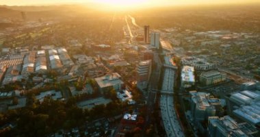 Los Angeles, California, ABD manzarasını geçen hareketli bir otoyol. Güneşin batışının ışığı metropolün manzarasını kamaştırıyor. Hava perspektifi.