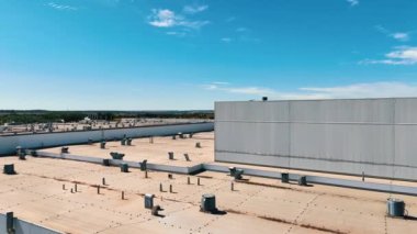 Üstünde birden fazla havalandırma pompası olan devasa bir sanayi fabrikasının çatısı. Şehirden uzaktaki modern fabrikanın hava manzarası.