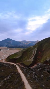 İzlanda 'nın çorak kayalık arazisi. Üzerinde bitki örtüsü olmayan dağlar ve vadiyi geçen dar nehirler. Dikey video.