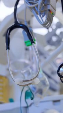 Hekimin steteskopu cerrahi odasındaki bir ekipmana asılı. Teçhizat tüpleri arka planda bulanık. Düşük açı. Dikey video