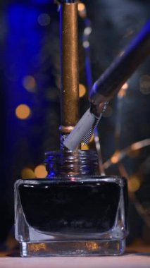 Robot Da Vinci bir kalem tutuyor ve mürekkeple şişeye batırıyor. Karanlık, bulanık bir zemin ve biraz da ışık. Dikey video