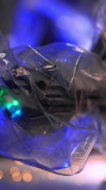 Plastikle kaplanmış, üzerinde ışıklar olan robot kol çalışıyor. Kapatın. Çelenk ışıklarıyla bulanık, karanlık bir zemin. Dikey video