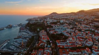 Dağ yamacının tepesindeki birçok beyaz evin turuncu çatıları. Portekiz 'in Madeira Adaları' ndaki şehrin günbatımı manzarası. Üst perspektif.