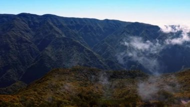 Portekiz, Madeira Adaları 'ndaki yüksek dağların nefes kesici manzarası. Hafif bulutlar kayaların üzerinde yüzer. Hava görünümü.