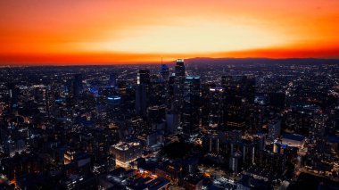 Vast panorama of a stunning Los Angeles, California, USA at twilight time. City scenery at the backdrop of orange sky. Aerial perspective. clipart