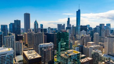 Chicago, Illinois, ABD merkezindeki yüksek binalara uçuyor. Binaların cepheleri parlak yaz güneşiyle aydınlanıyor..