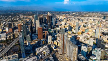 Sabahın köründe şehir merkezindeki Los Angeles gökdelenlerinin cephelerini aydınlatan parlak güneş. Kalın sis, arka plandaki bir şehrin manzarasını kaplıyor. Hava perspektifi.