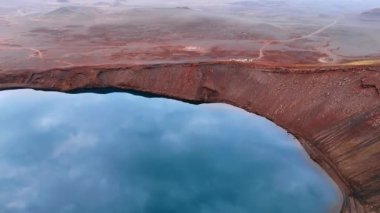 Mavi gökyüzü, uyuyan krater volkanındaki göle yansıyor. İzlanda 'nın kayalık arazisinin üstündeki insansız hava aracı görüntüleri.