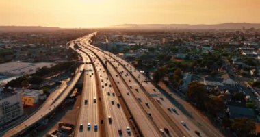 Parlak güneş ışığıyla aydınlatılmış otobanlardan arabalar geçiyor. Ulaşım Los Angeles, Kaliforniya, ABD 'de. Yukarıdan gün batımı görünümü.