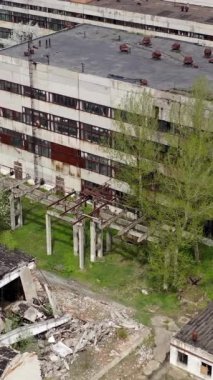 Hasarlı antik fabrika. İlkbaharda bozulmuş endüstriyel eski fabrika. Yıkık binaları olan terk edilmiş bir yer. Hava görüntüsü. Dikey video