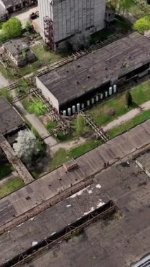 Rusty terk edilmiş fabrika binalarının çatılarını yıktı. Baharda bir fabrikanın boş arazisi. Hava görüntüsü. Dikey video