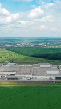 Endüstriyel arazi. Yeşil doğayla çevrili büyük bir fabrika. Yeşil alan arka planında endüstriyel fabrika. Hava görüntüsü. Dikey video