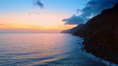Madeira Adaları 'nın karanlık kayaları Kuzey Atlantik Okyanusu' nun dalgalarıyla buluşur. Gün batımında güzel pembe gökyüzü ufukta.