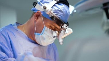 Odaklanmış beyaz erkek cerrah ameliyat yapıyor. Cerrahi hoparlörlerdeki doktor metal aletler kullanıyor. Kapat..