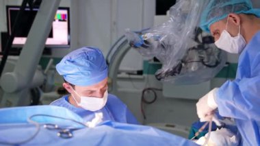 Erkek cerrah ve asistan ameliyathanede çalışıyor. Doktora yardım etmek doktor için gerekli malzemeleri hazırlar..