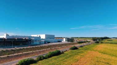 Önünde park yeri olan büyük bir sanayi fabrikasıyla aradaki mesafe. Fabrikanın etrafındaki tarım arazileri ve ormanlar. Hava görünümü.