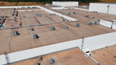 Büyük sanayi fabrikasının çatısındaki havalandırma boruları ve bacalar. Şehrin çok ötesindeki işletmenin üzerinde uçuş.