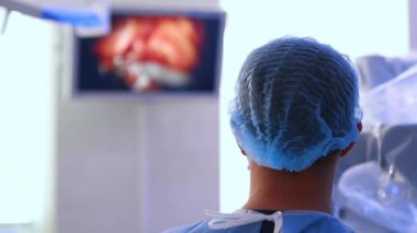 Dikiz aynasındaki doktorun başı. Erkek cerrahın boynu yakın çekim. Görüntü arkaplanda cerrahi görüntüleme ekranı.