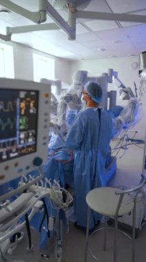 Modern cerrahi odasındaki robotik ekipmana yaklaşıyoruz. Doktor Da Vinci Cerrahi Sistemi 'nde asgari invazif ameliyat yapıyor. Dikey video.
