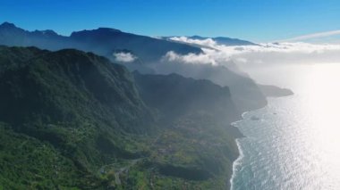 Portekiz 'in Madeira Adaları' ndaki sahilin manzarası. Hava perspektifi bulutlarla kaplı çarpıcı dağlara ve parlak güneşle göz kamaştırıcı.