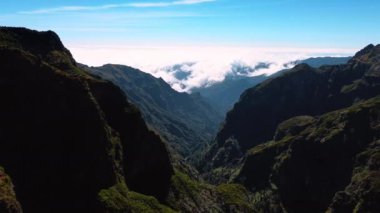 Portekiz 'in Madeira Adaları' ndaki tehlikeli dağlara ulaşılamıyor. Arkaplanda kayaların tepelerini beyaz bulutlar kaplıyor. Üst görünüm.