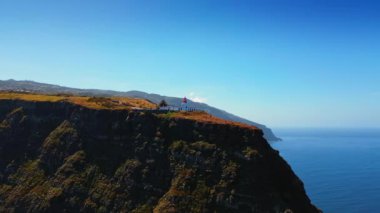 Tepesinde güzel bir deniz feneri olan sarp kayalıkları olan dev dağlar. Portekiz, Madeira Adaları kıyısı manzarası. Hava görünümü.