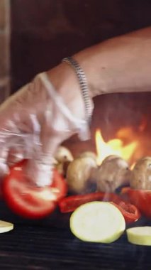 Organik gıda ızgarası. Profesyonel bir aşçının eli taze sebzeleri fırına koyuyor. Lezzetli kompozisyon yanıyor. Sağlıklı yiyecekler. Dikey video