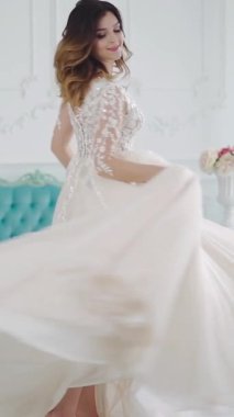 Işık odasında güzel bir gelin. Beyaz stüdyo içinde güzel elbiseli gelin. Evde dikey videodaki gibi.