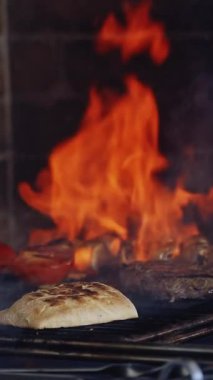 Ateşte yemek pişirmek. Şef tarafından ızgara hazırlanmış leziz bir yemek. Mangalda sebzeler. Yemek bulaşıkları sırasında parlak bir alev. Dikey video