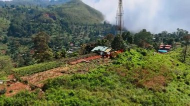Bazı insanlar haberleşme kulesinin yanındaki meyve bahçesinde duruyor. Arka planda dağı kaplayan devasa bulut manzarası. Sri Lanka, Güney Asya.