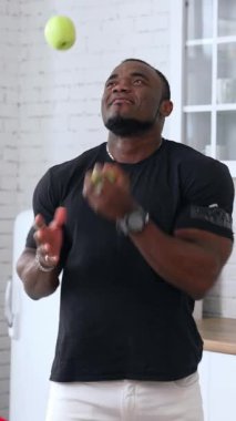 Mutfak arka planında elma güden, seçici odaklanan, yakın plan mutlu genç adam. Diyet konsepti. Sağlıklı bir adam dikey meyve kusuyor.