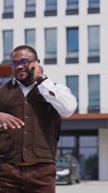 Yakışıklı iş adamının belden aşağı portre görüntüsü ailesiyle, arkadaşlarıyla ya da ortaklarıyla dostça görüşüyor. Genç adam güneşli bir günde iş bölgesinde yürüyordu.