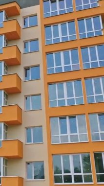Şehirde modern bir bina inşa ediliyor. Şehirde plastik pencereleri olan çok katlı bir apartman dairesi. Yeni bir mimari konsepti oluşturuluyor. Dikey video