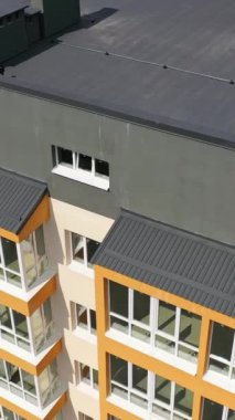 Çok katlı binanın güzel tasarımı. Mavi gökyüzüne karşı balkonları olan yeni bir daire. Konut binasının dışı. Kamera yükseliyor. Yavaş çekim Dikey video