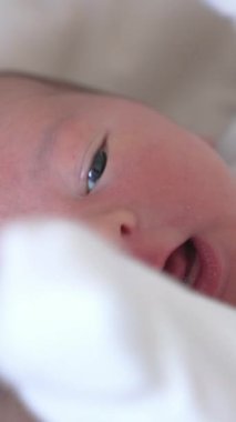 Tapılası yeni doğmuş bebeğin yüzü. Evdeki yatakta duran sağlıklı, tatlı bir çocuk portresi. Mutlu bir aile ilişkisi ve yeni doğmuş bir bebek. Dikey videoyu kapat