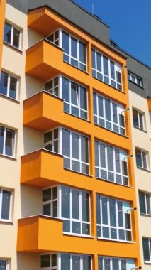 Şehirde modern bir bina inşa ediliyor. Şehirde plastik pencereleri olan çok katlı bir apartman dairesi. Yeni bir mimari konsepti oluşturuluyor. Dikey video