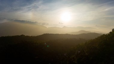 Sri Lanka dağları üzerinde huzurlu bir günbatımı. Sri Lanka 'nın yemyeşil dağlarının üzerinde turuncu ve altın rengi gökyüzünü nefes kesen bir günbatımı, huzurlu bir akşam atmosferi yaratıyor..