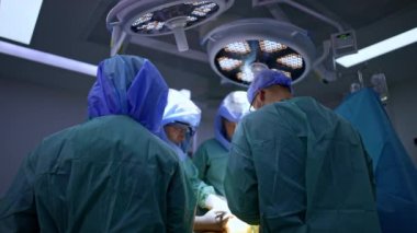 Üniformalı bir grup doktor ameliyat masasının etrafını sardı. Kooperatif cerrahlardan oluşan bir ekip travma ameliyatını gerçekleştirir. Düşük açı görünümü.